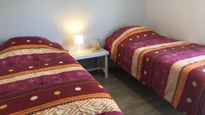 A room with two beds, each with patterned bedding, a small table with a lamp and a glass pitcher. - Chalet N° 5 - SAINT SECONDIN (SAINT SECONDIN)