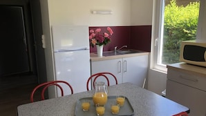 A kitchen with a refrigerator, a sink, a microwave, and a table with chairs. There is a tray with juice glasses on the table. - Chalet N° 5 - SAINT SECONDIN (SAINT SECONDIN)