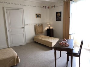 Ett sovrum med en säng, ett bord med en lampa, en stol, en garderob och en dörr.