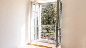 Ein Schlafzimmer mit einem Bett, einem kleinen runden Tisch und einem Fenster mit freiem Blick ins Freie.