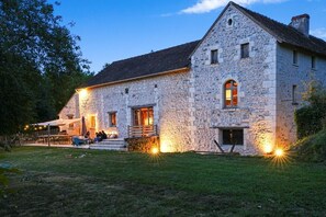 A stone building with a porch, steps, and a well-lit entrance. - The Gaudais mill (OYRE)
