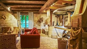 Un interior rústico con paredes de piedra, techo de madera, un sofá rojo y una chimenea de piedra.