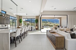 A modern kitchen with a bar area, dining space, and a living area with a view of mountains. - NEW Luxury|Pool|Spa|Sevens Escape at Sereno Canyon (Scottsdale)