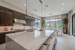 A modern kitchen with a large island, dark wood cabinets, stainless steel appliances, and pendant lighting. - NEW Luxury|Pool|Spa|Sevens Escape at Sereno Canyon (Scottsdale)