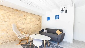 Ein modernes Wohnzimmer mit einer Steinwand, einem grauen Sofa, einem weißen Tisch und einem gemusterten Teppich.