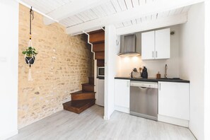 A kitchen with white cabinets, a stainless steel dishwasher, and a hanging plant. - Le Gite du Cèdre - MONTAMISE (MONTAMISE)