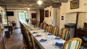 A long dining table set with chairs, a television mounted on the wall, and a fireplace.