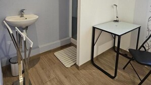 Ein modernes Badezimmer mit Waschbecken, Spiegel und einem kleinen Tisch mit Stuhl.
