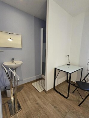 A modern bathroom with a sink, mirror, and a small table with a chair. - La Blanche Maille - CISSE (CISSE)