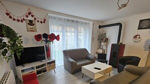 Ein Wohnzimmer mit Fernseher, Sofa, Sesseln und einem Kamin.