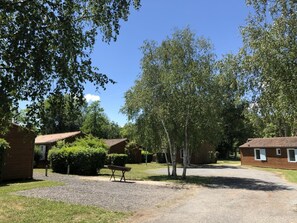 A campground with multiple cabins, a gravel driveway, and a bench. - Chalet N° 4 - SAINT SECONDIN (SAINT SECONDIN)