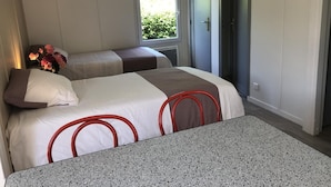 Une chambre avec deux lits, une table et une fenêtre.