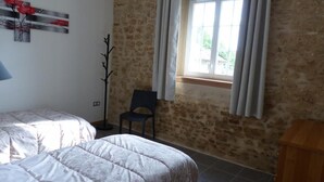 Una camera da letto con due letti, una finestra con tende, una sedia e una lampada.