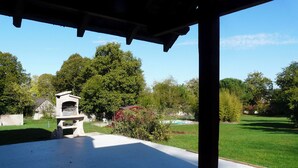 Un patio abrité équipé d’un barbecue, une piscine et une pelouse bien entretenue.