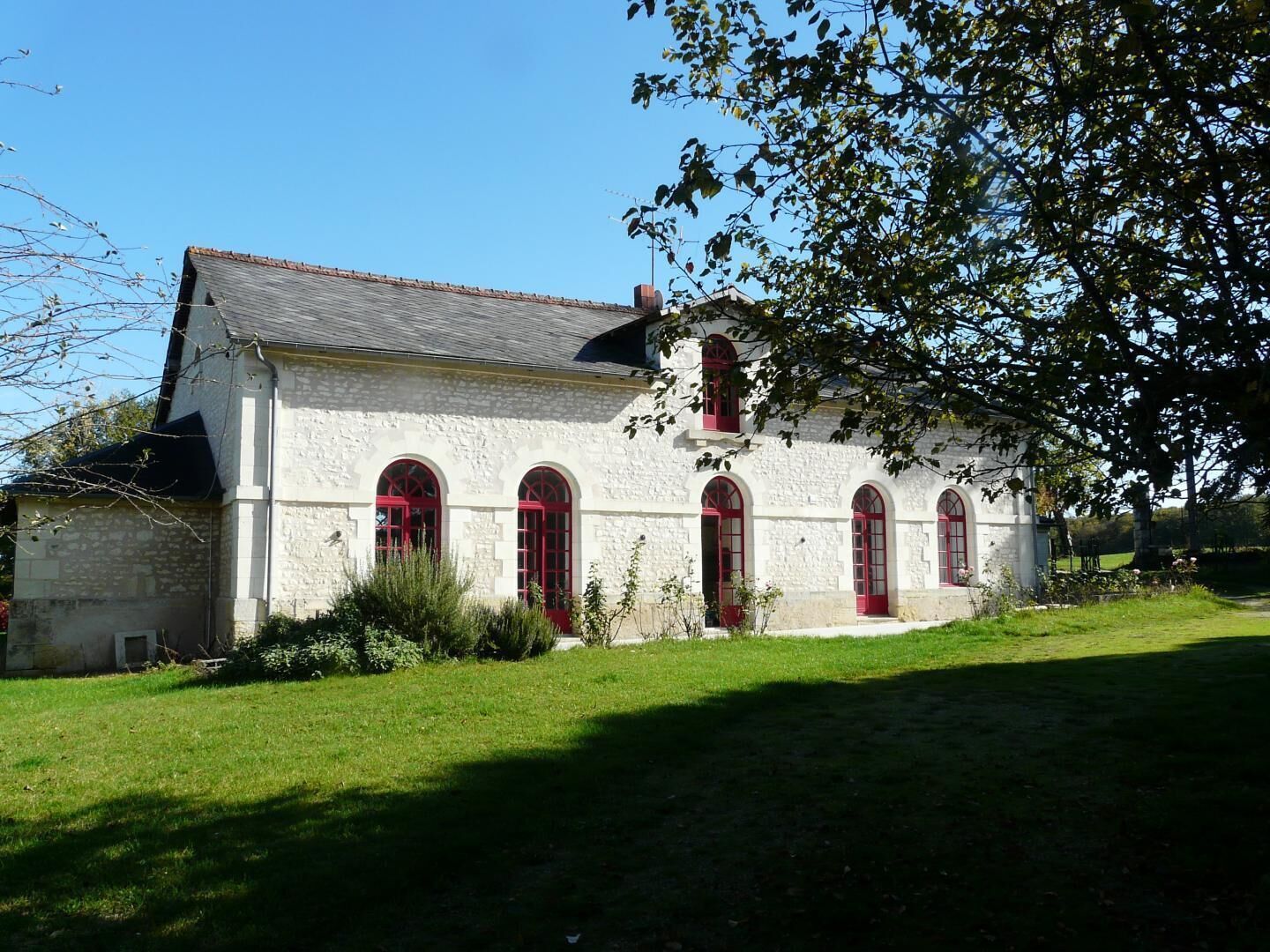 A stone building with arched windows and a red door.