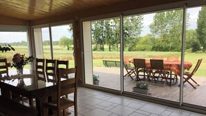 A room with a large sliding glass door leading to an outdoor patio with a table and chairs. - La Prée - SERIGNY - Gîte (SERIGNY)