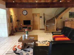 Ein Wohnzimmer mit einer Holztreppe, einem Fernseher und einer Wanduhr.