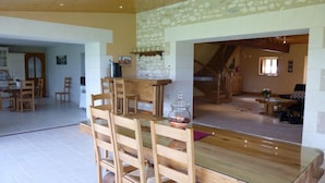 A spacious dining area with a wooden table and chairs, a stone wall, and a staircase leading to another level. - La Prée - SERIGNY - Gîte (SERIGNY)