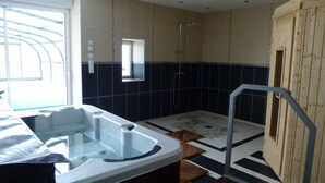 A modern bathroom with a glass-enclosed jacuzzi, a wooden sauna, and a shower area. - La Prée - SERIGNY - Gîte (SERIGNY)