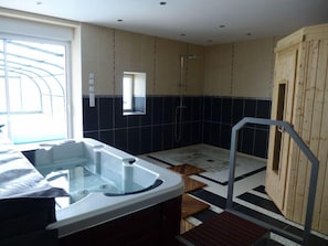 Ein modernes Badezimmer mit einer Glaskuppel-Whirlwanne, einer Holzsauna und einer Duschkabine.
