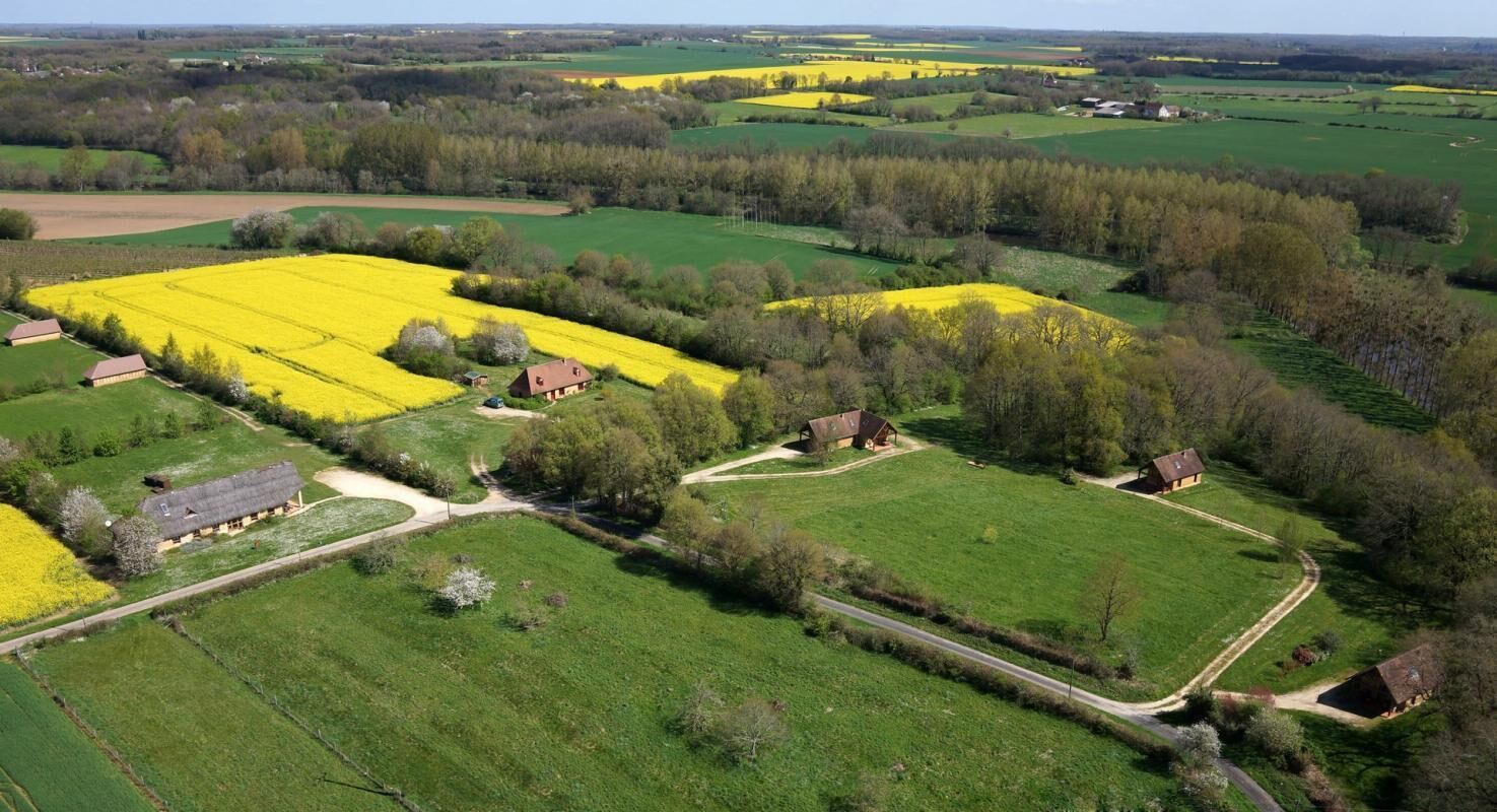 Une vue aérienne d’un paysage rural, avec des champs, des arbres et des fermes.