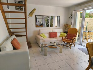 A living room with a sofa, armchair, coffee table, and a staircase. - La Royannaise" house by the sea (Royan)