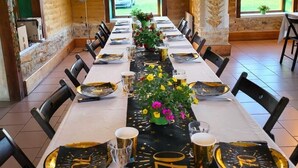 Ein langer Esstisch, gedeckt mit gold- und schwarzfarbigem Geschirr, mit floralem Mittelstück und Ballons.