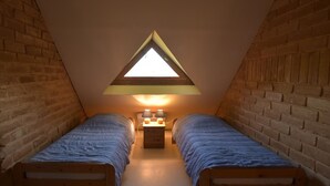 Ein kleines Schlafzimmer im Dachgeschoss mit zwei Einzelbetten, einem Nachttisch und einem Dachfenster.