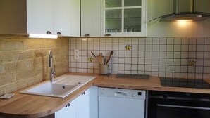 Una cocina con pileta, lavavajillas, horno y alacenas.