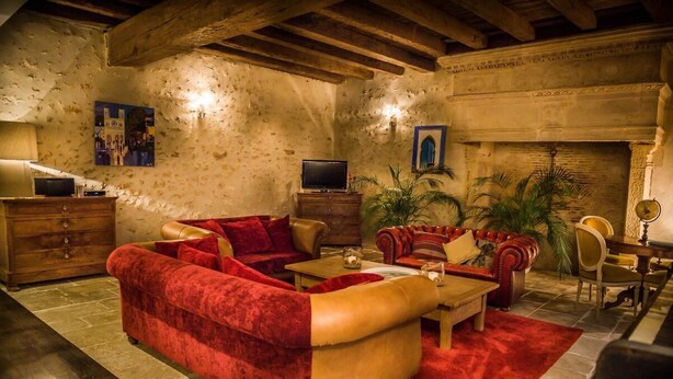 Una sala de estar acogedora con un sofá rojo, una mesa de centro de madera y una chimenea.