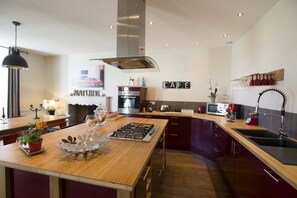 Una cocina moderna con una isla central, horno empotrado y un cartel con la palabra 'CAFE'.