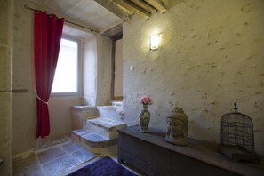 A room with a window, a red curtain, a vase with flowers, a Buddha statue, and a birdcage. - Le Clos Mélior - LUSIGNAN (LUSIGNAN)