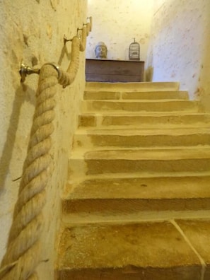 A stone staircase with a rope handrail, a small Buddha statue, and a birdcage on a shelf. - Le Clos Mélior - LUSIGNAN (LUSIGNAN)