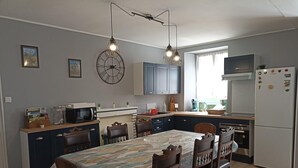 Una cocina moderna con comedor, que incluye un reloj, armarios y un refrigerador.