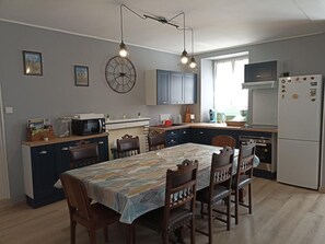 Eine moderne Küche mit Essbereich, ausgestattet mit einer Uhr, Schränken und einem Kühlschrank.