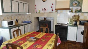 A kitchen with a dining table, chairs, a stove, a microwave, a washing machine, and cabinets. - This is Paradise (SENILLE-SAINT-SAUVEUR)