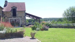 A stone building with a covered porch, a gravel driveway, and a well-maintained garden with various plants and flowers. - This is Paradise (SENILLE-SAINT-SAUVEUR)