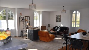 A spacious living area with a dining table, orange armchairs, a sofa, and a metal cabinet. - Le Moulin Brûlé - BETHINES (BETHINES)