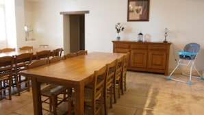 A dining area with a wooden table and chairs, a cabinet, and a baby high chair. - Les Cèdres - BLANZAY - Gîte (BLANZAY)