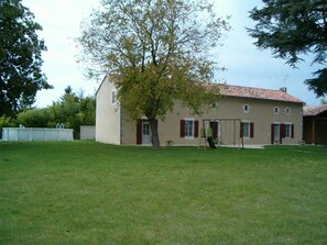 A two-story house with a red-tiled roof, a small garden, and a tree in front. - Les Cèdres - BLANZAY - Gîte (BLANZAY)