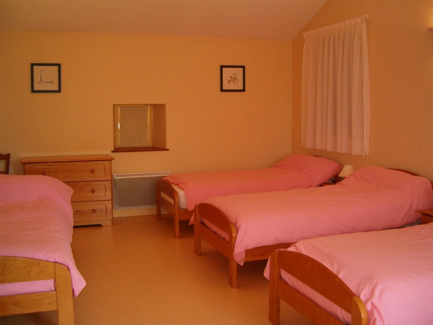 A bedroom with two single beds, a wooden dresser, a mirror, and two framed pictures on the wall.