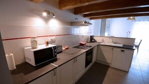 Una cocina con armarios blancos, microondas, tostadora, cafetera y lavavajillas.