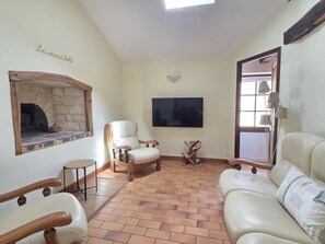 Ein Wohnzimmer mit Kamin aus Stein, einem Flachbildfernseher und einem großen Fenster.