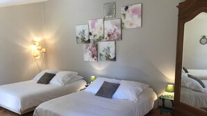 Hotellihuone, jossa on kaksi sänkyä, peili, seinälle ripustettu taideteos ja yöpöytävalaisimet.