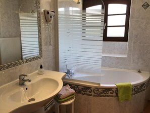 A bathroom with a sink, mirror, hairdryer, window, and bathtub. - La Chèvrerie - MARCAY - Gîte (MARCAY)