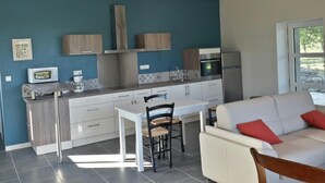 Cocina moderna con comedor, que incluye una mesa blanca, sillas y un sofá con cojines rojos.