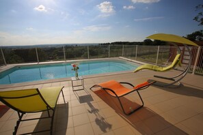 A rooftop pool with a view of the landscape, surrounded by a metal fence, and includes two lounge chairs and a small table with a vase of flowers. - Gîte Montgolfière - CHATELLERAULT (CHATELLERAULT)
