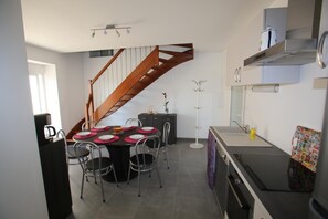 A modern kitchen with a dining area, a staircase, and a built-in oven. - Gîte Montgolfière - CHATELLERAULT (CHATELLERAULT)