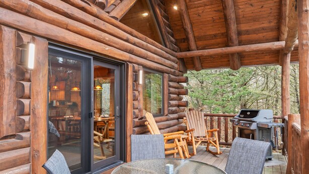 A log cabin with a glass door, outdoor seating, and a grill. - Rustic Ridge Cabin 104 - Private Woodland Retreat near Devil's Lake State Park (Merrimac)