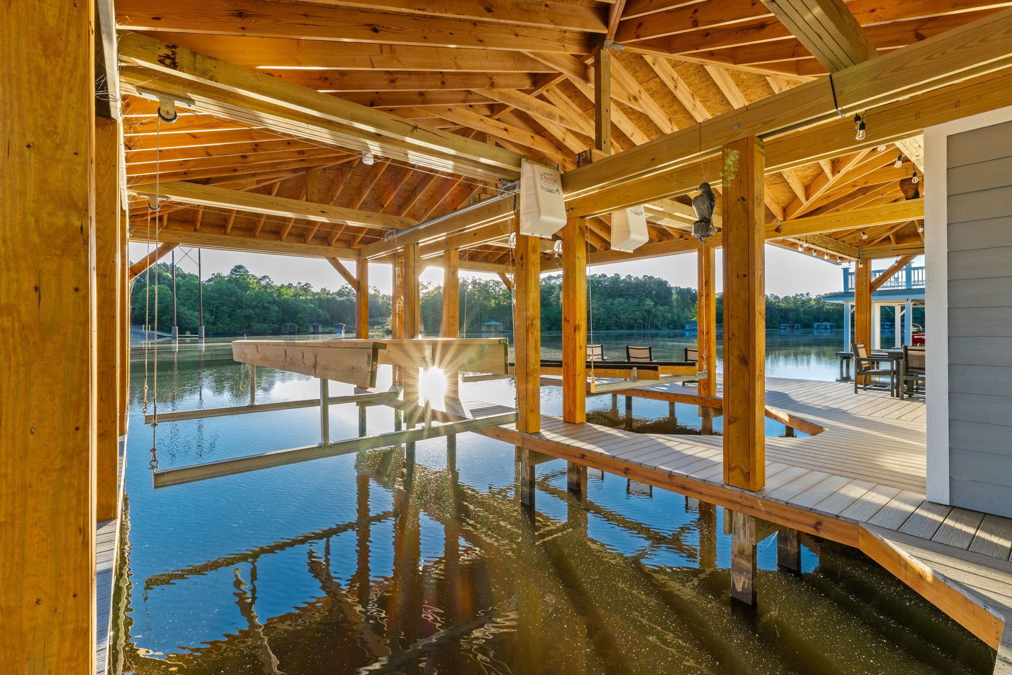 A wooden deck extending over water with a clear view of the lake, wooden beams, and a bench area.